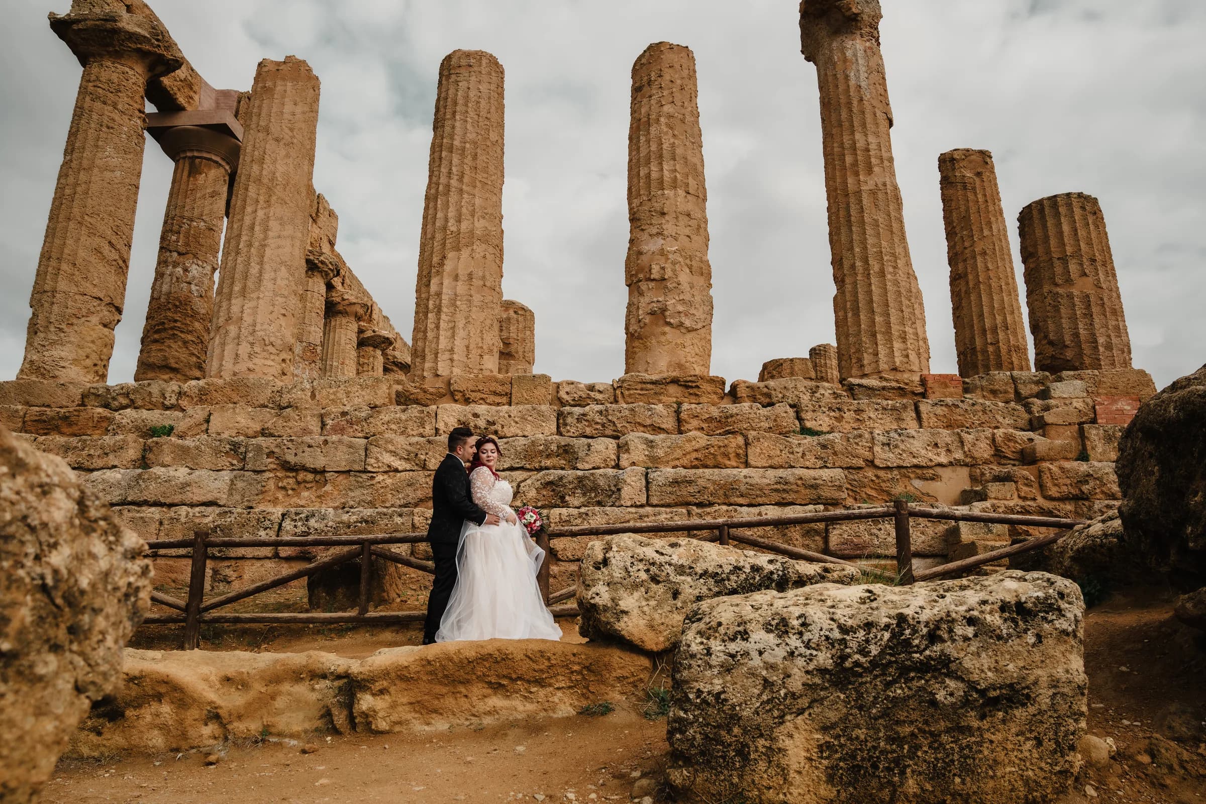 A bride and groom framed between temple columns and weathered stone