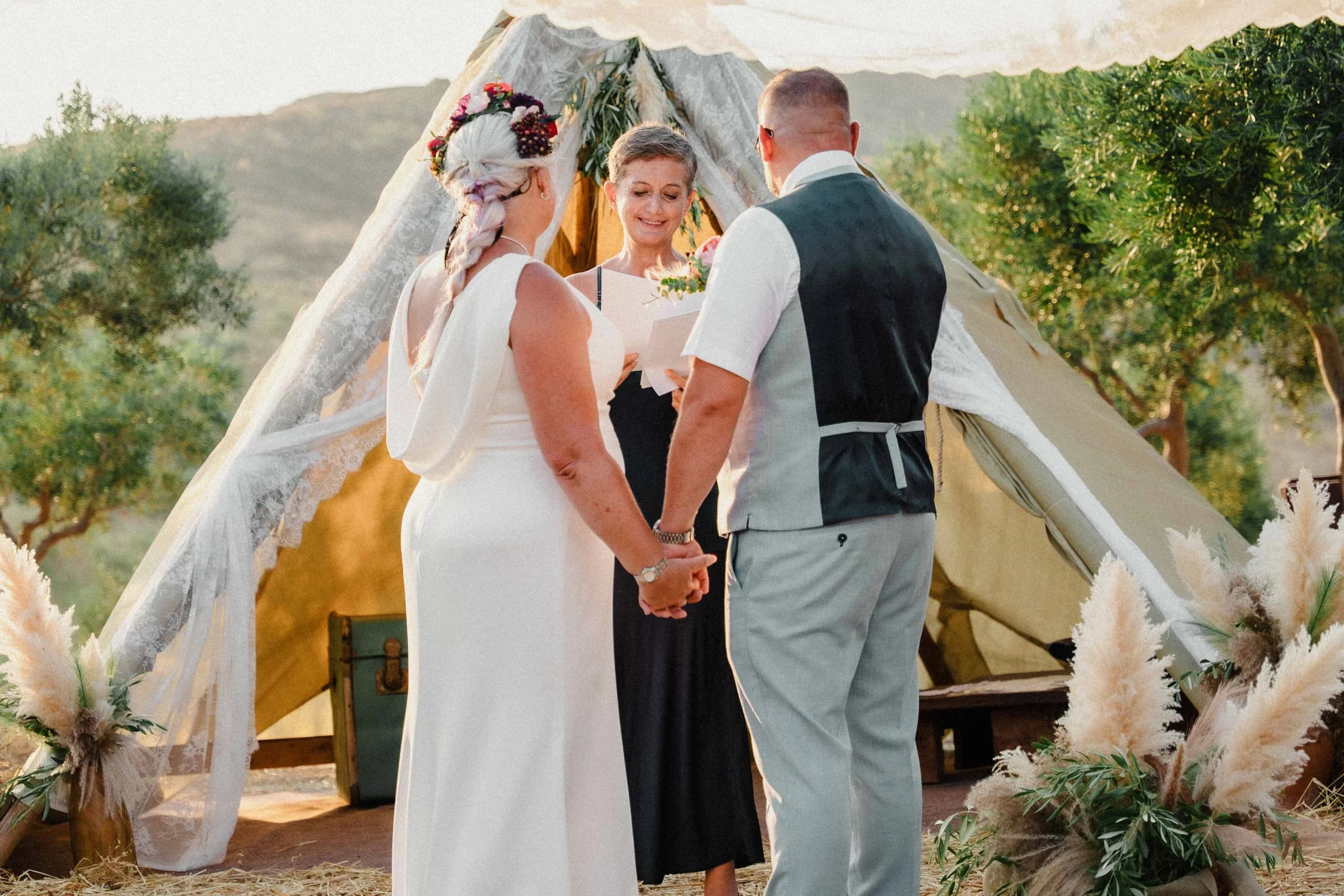 The couple holding both hands during their vows, the celebrant between them