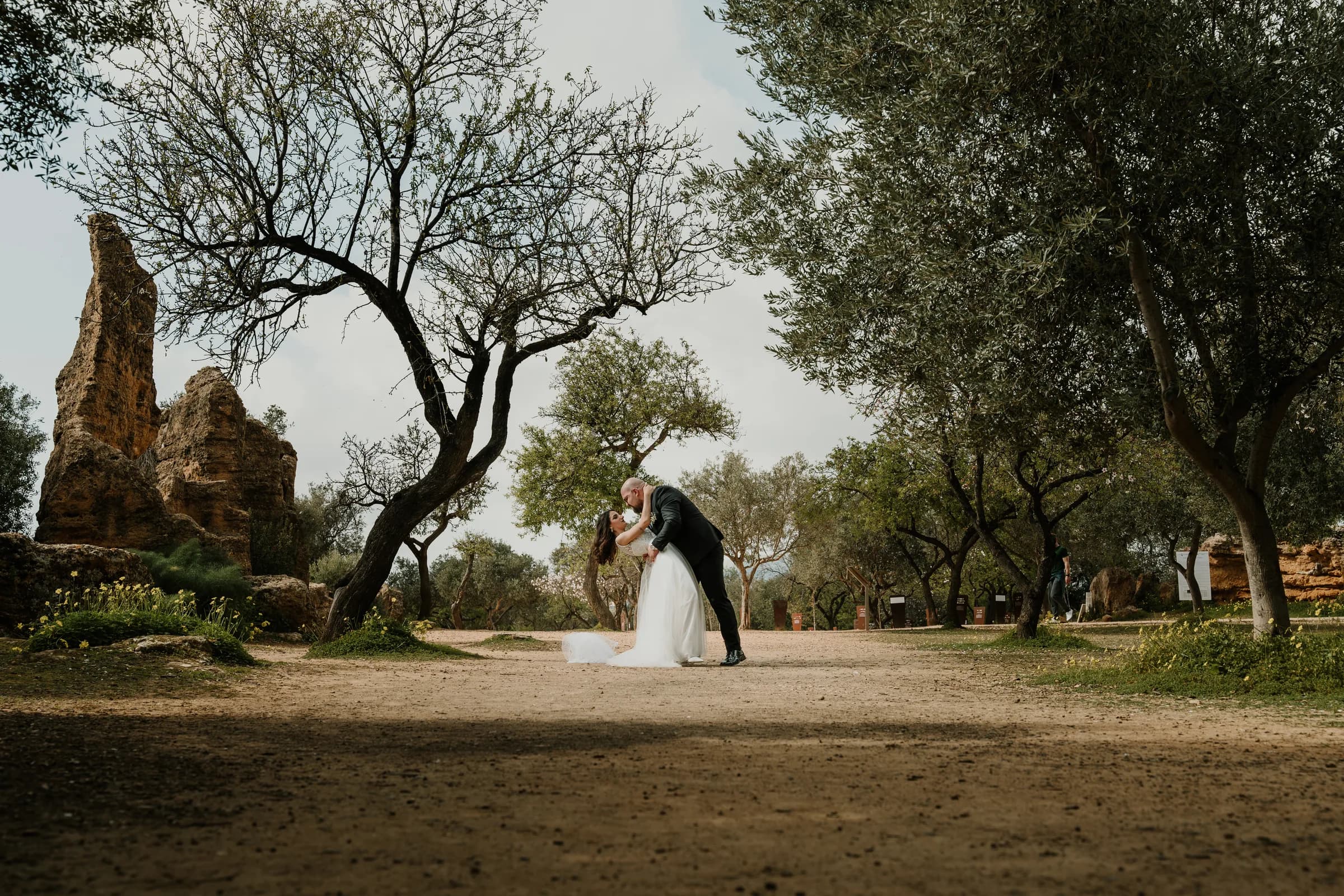 A couple alone on a wide path among olive trees and ruins
