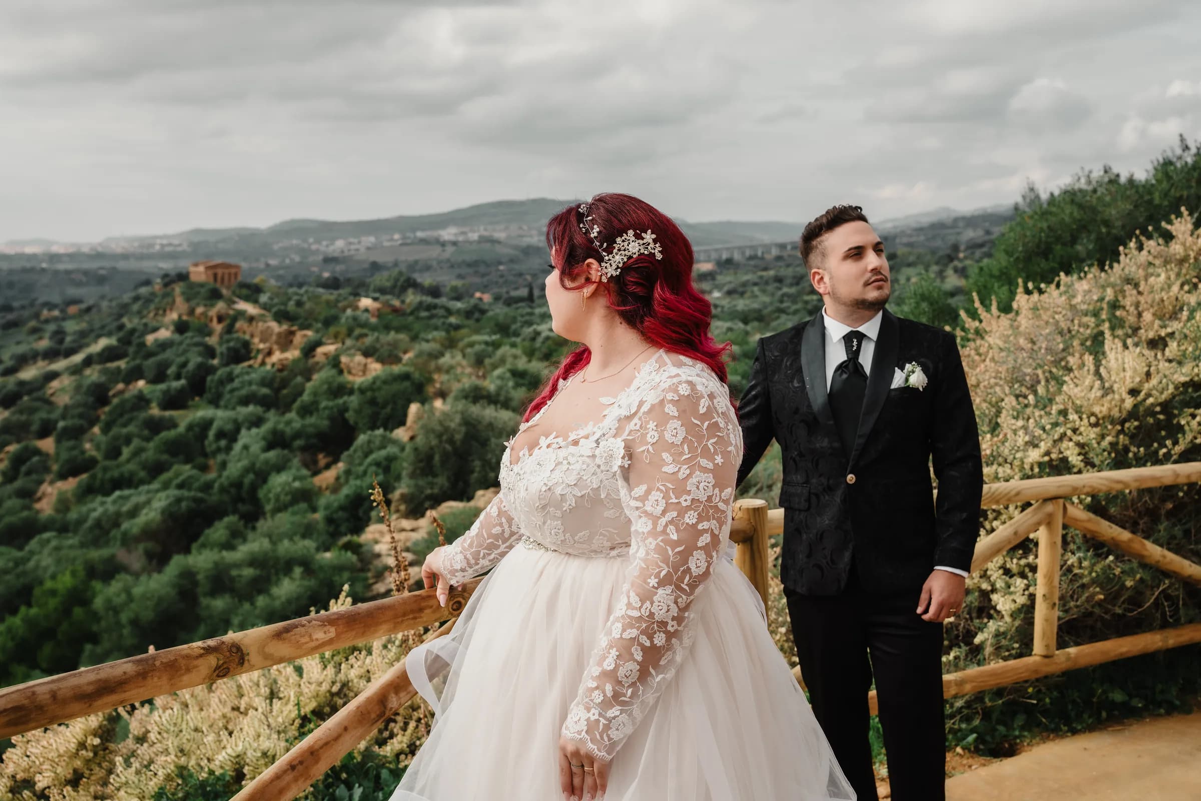 A couple on a terrace overlooking a valley of olive groves